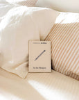 In the Margins career journal resting on white pillows and a striped blanket