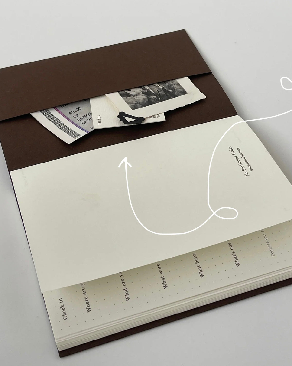 Open Off the Grid travel journal showing its back pocket holding tickets and photos