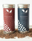 Nu Chocolat Signature Blend and 65% Dark hot chocolate tins on chocolate shavings