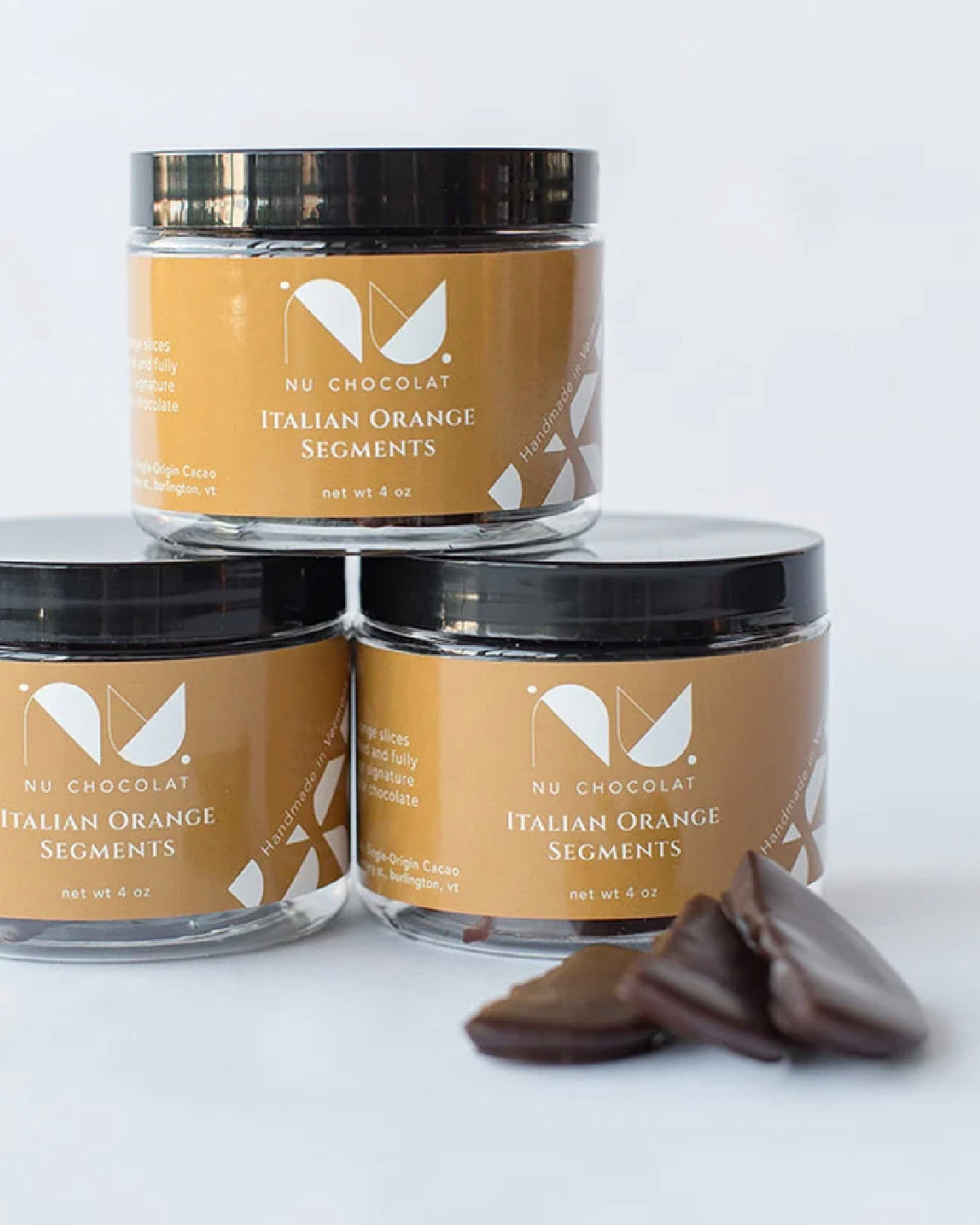 Three jars of Nu Chocolat Italian Orange Segments with chocolate-dipped orange pieces in front