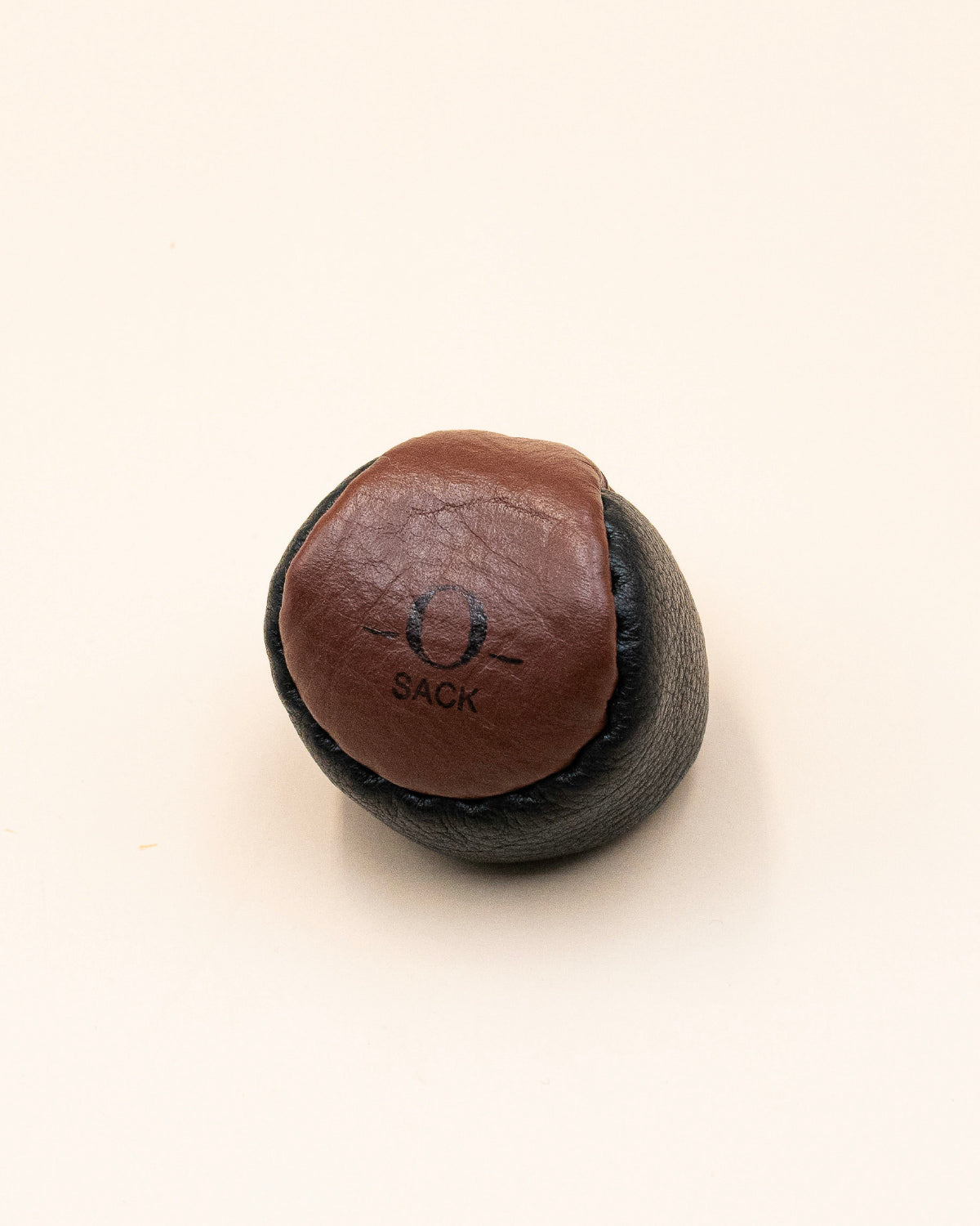 Single brown leather O-Sack hacky sack with a black panel and stamped logo