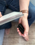 Hand holding a black ONO fidget roller while reading on a couch