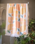 Turkish cotton towel with orange and green pattern hanging in a bathroom.