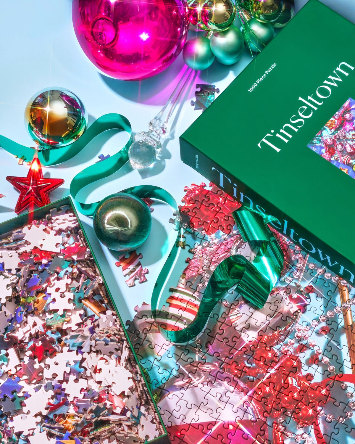 Tinseltown puzzle in progress with loose pieces, ornaments and its green box