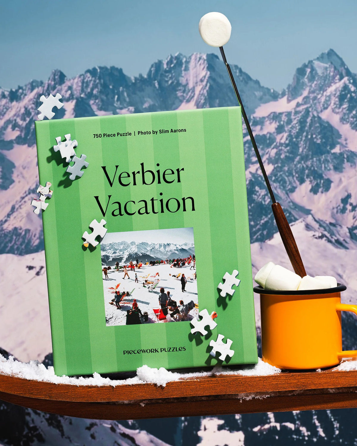 Verbier Vacation puzzle box with scattered pieces beside an orange mug in the mountains