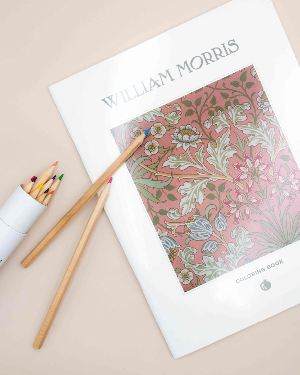William Morris Florals coloring book with a pink floral cover beside colored pencils