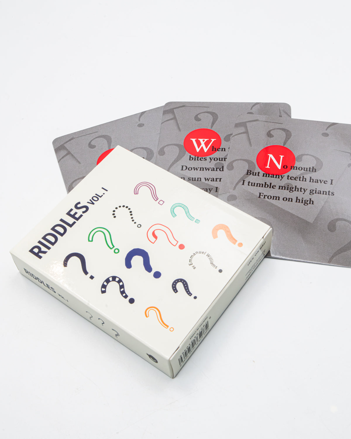 Riddles Vol. 1 card deck box resting on scattered riddle cards