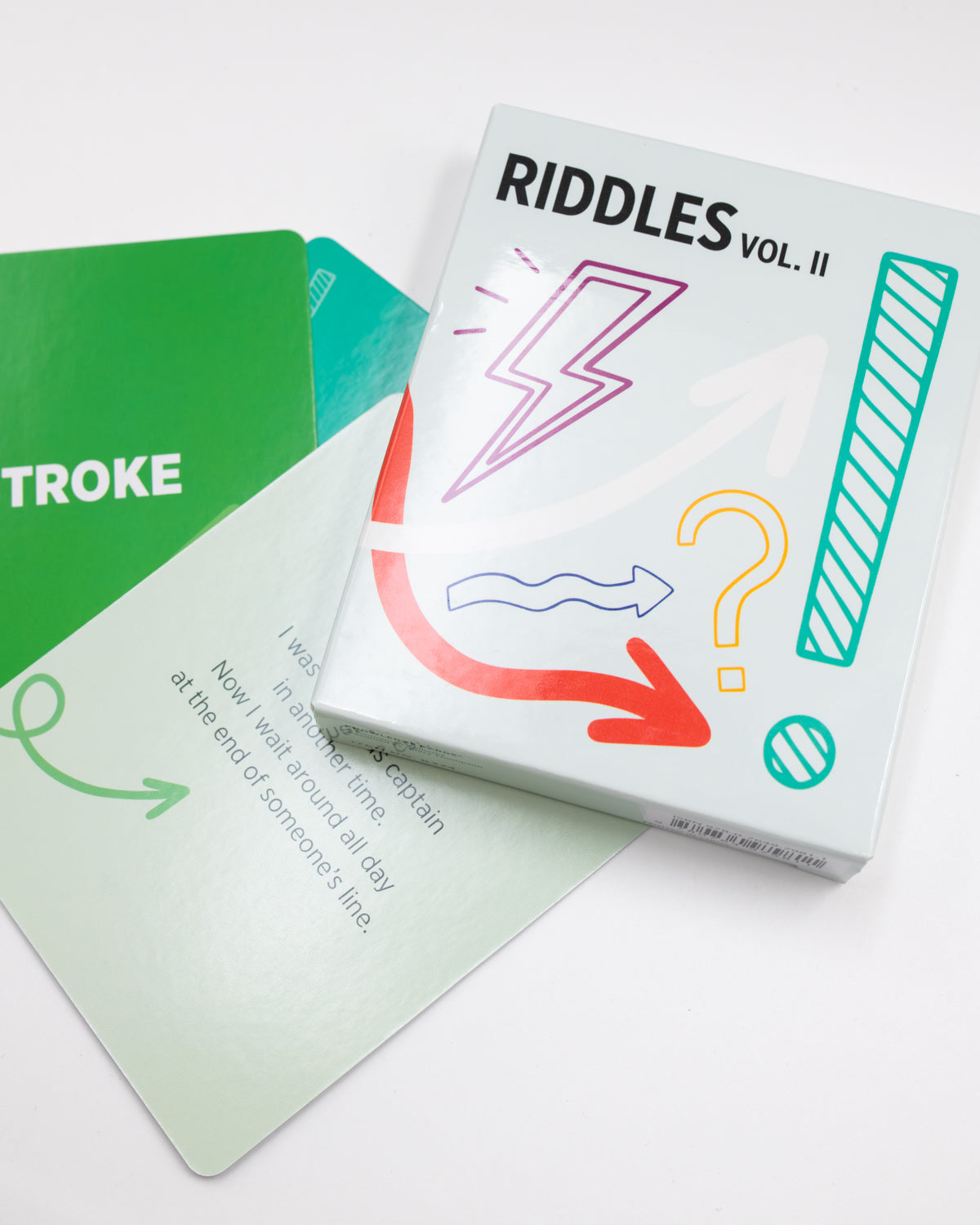 Riddles Vol. 2 card deck box resting on scattered riddle cards