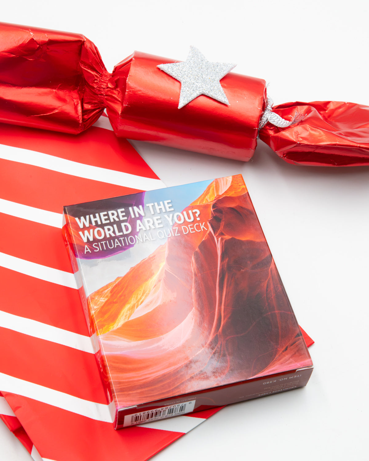 Where in the World Are You? situation card deck box in front of a red holiday cracker