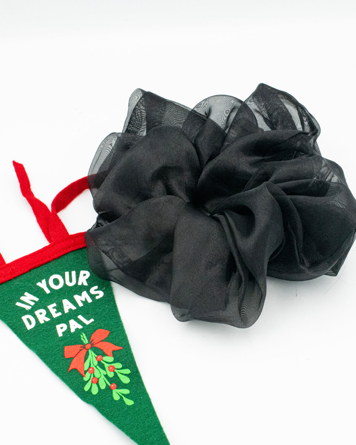 Oversized, black organza scrunchie next to a felt holiday banner with misletoe