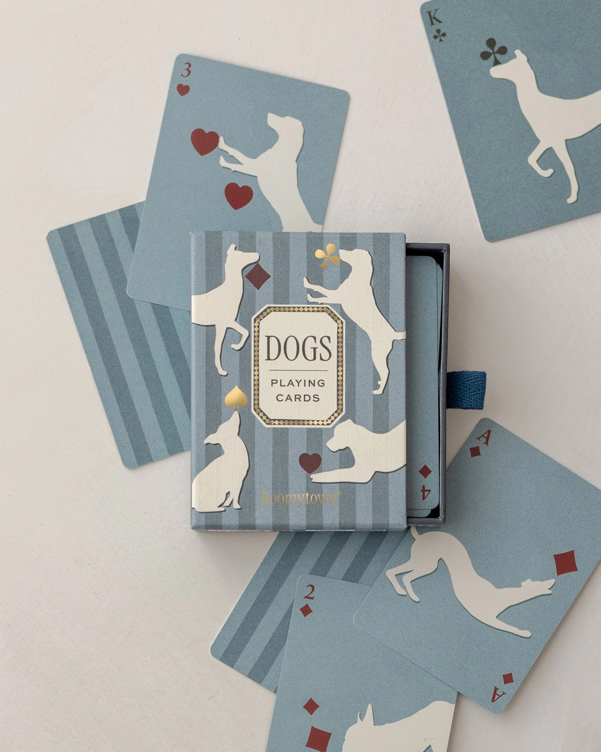 Roomytown Dogs playing card deck in a blue striped box with cards showing cream dog silhouettes
