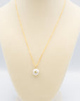 Pearl with set-in peridot gemstone on a gold paperclip chain necklace