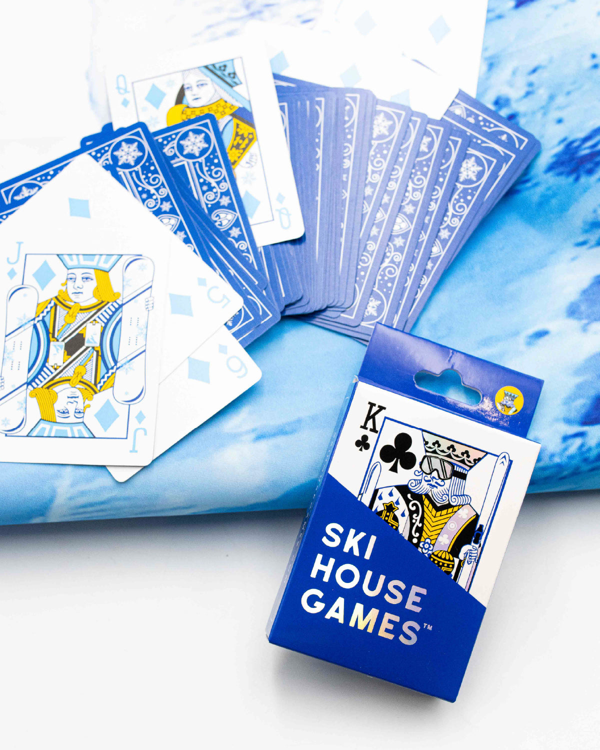 Ski House Games deck fanned out with blue card backs and a skier jack beside the box