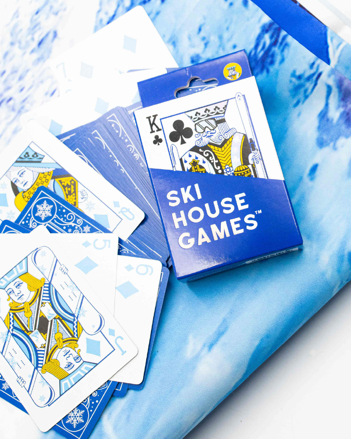 Ski House Games playing cards with skier face cards spread on a blue snow print
