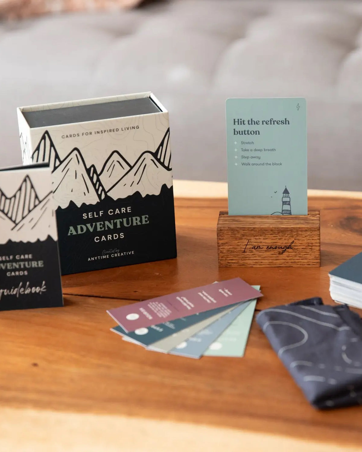 Self Care Adventure Cards box, guidebook and fanned cards on a wooden coffee table