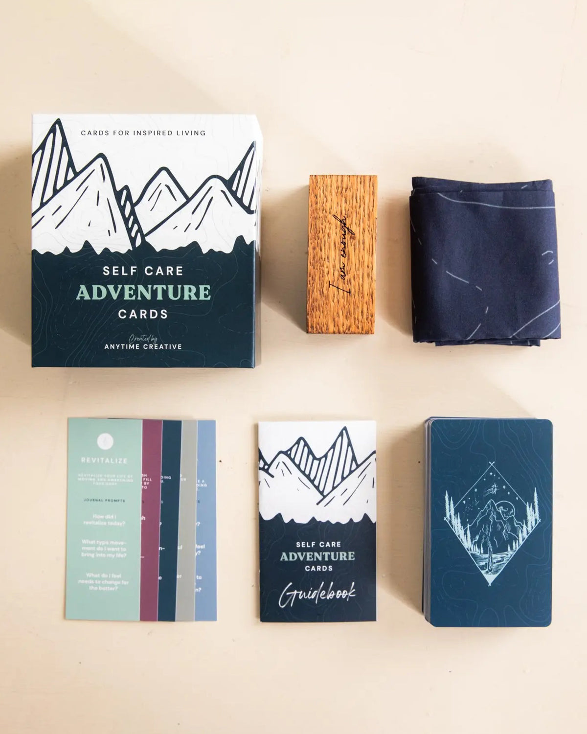 Self Care Adventure Cards set laid out with the box, wooden stand, cloth and guidebook