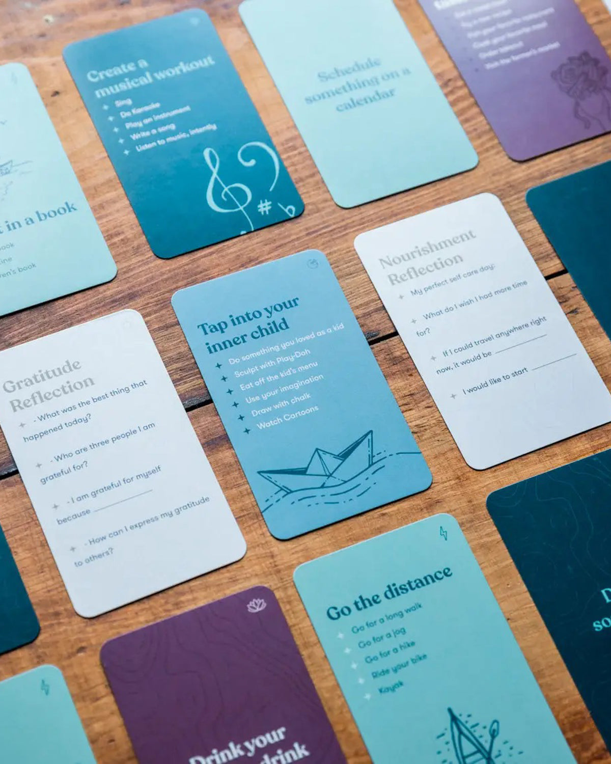 Self-care adventure cards spread on wood, with prompts like Go the distance