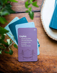 Plum Unplug card from the self-care deck fanned with blue cards on a wood table