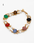 Vintage scarab bracelet with double pearl links and multi-colored carved stones laying flat on a white background