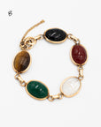 Close-up of a vintage scarab bracelet featuring 5 etched stones: tiger's eye, black onyx, rare clear quartz and carnelian stones
