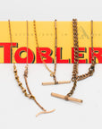 Three necklaces made from Victorian-era men’s watch chains with antique T-bars and dog clips. Authentic 100+ year-old pieces draped over a Toblerone bar