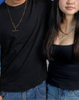 Close up of man and woman in black shirts and blue jeans wearing necklaces made with antique Victorian watch chains with t-bars and dog clips.