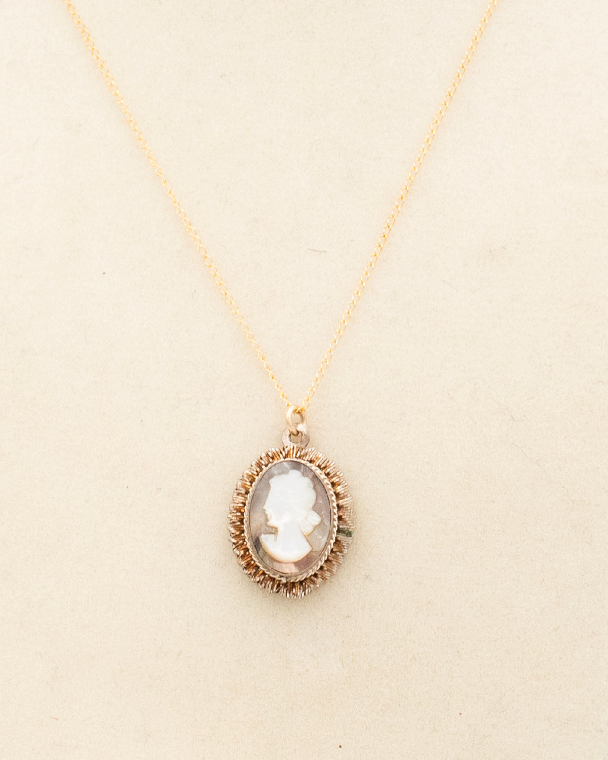 Close up of intaglio reverse-carved glass cameo pendant in gold-fill halo setting on 18&quot; chain on a jewelry bust. 