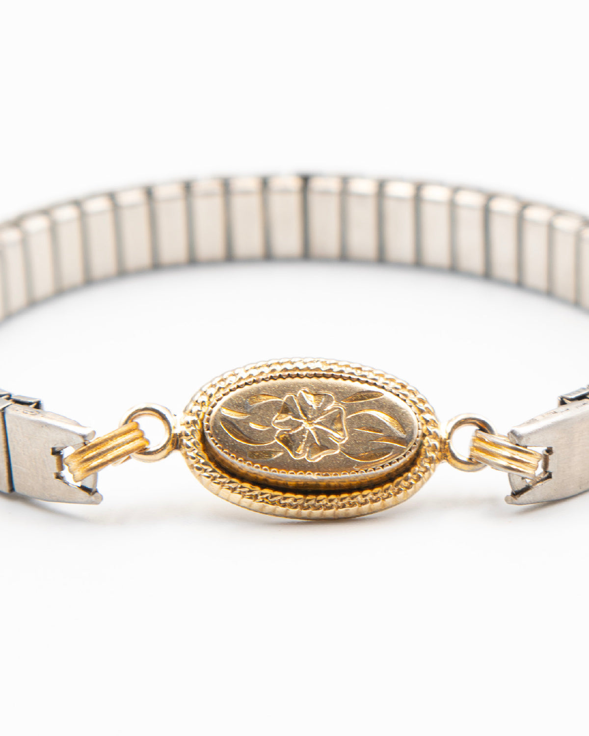 Close-up of the Candlelit Bloom etched gold-fill flower link on a steel expansion band