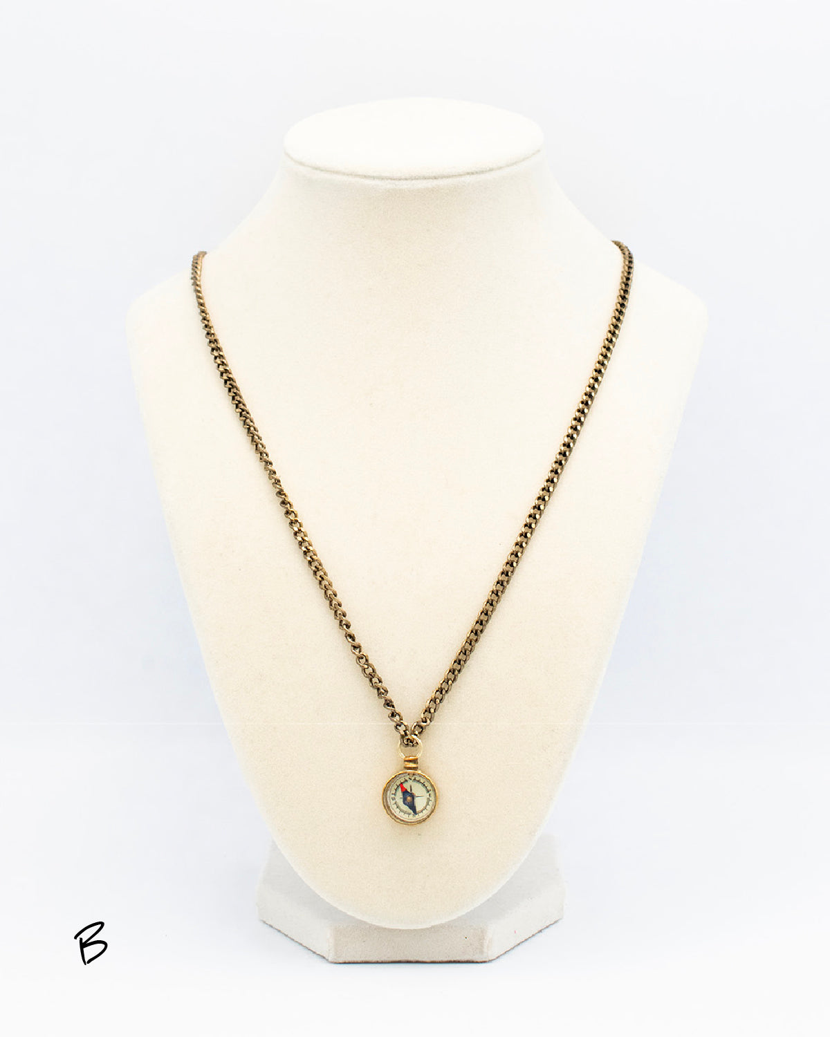 1970s compass pendant on brass chain displayed on a jewelry bust