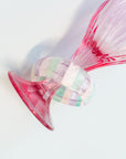 Close-up of a fluorite beaded bracelet draped over a pink glass vase, showing its translucent green, purple, and white striped beads.