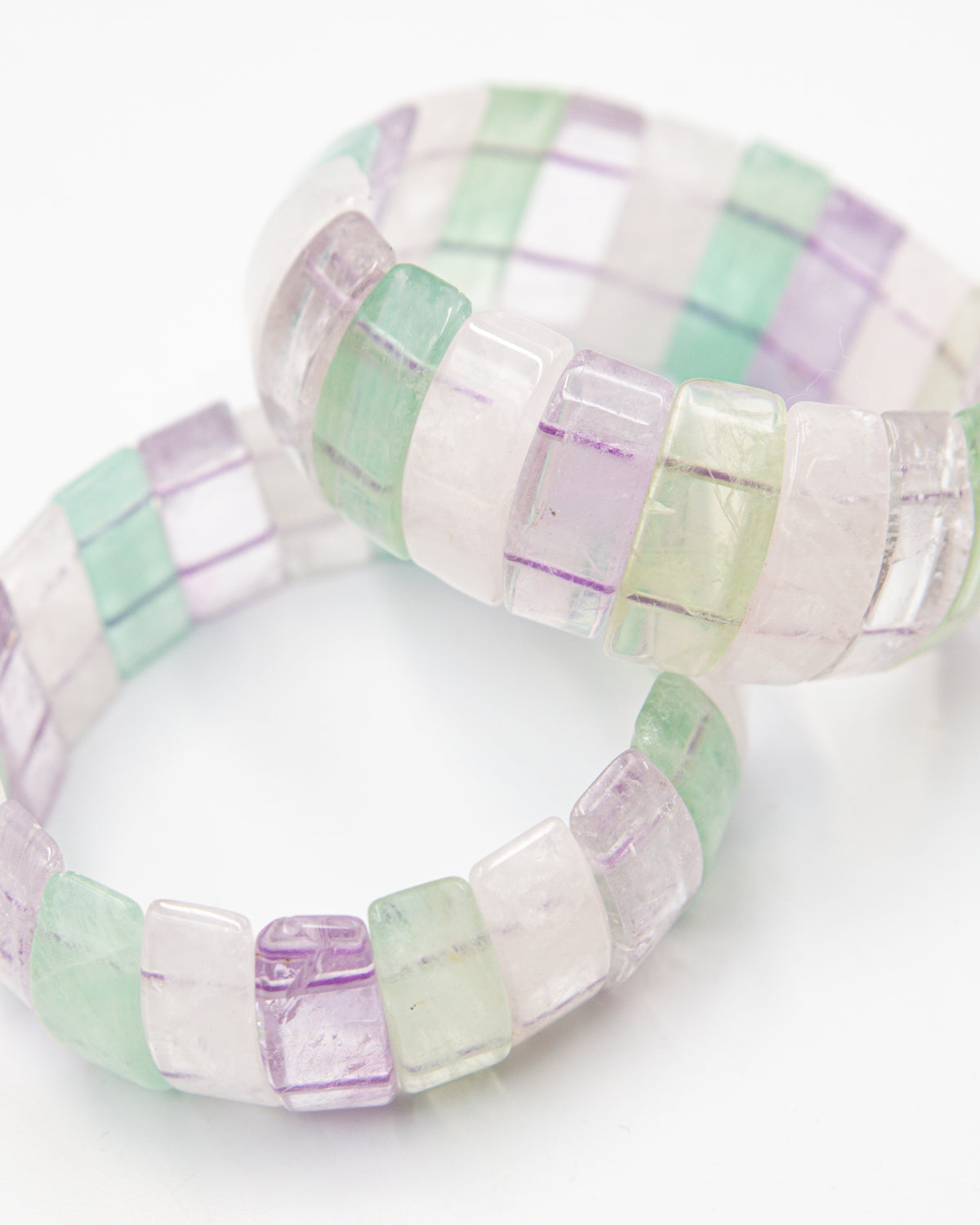 Close-up of two overlapping fluorite beaded bracelets highlighting the translucent green, purple, and clear banded stone beads.