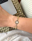 Close-up of a wrist wearing a gold-toned vintage bracelet with a decorative clasp.