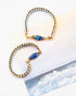 Two gold and silver beaded bracelets with lapis lazuli stones on a white surface.