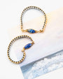 Two gold and silver beaded bracelets with lapis lazuli stones on a white surface.