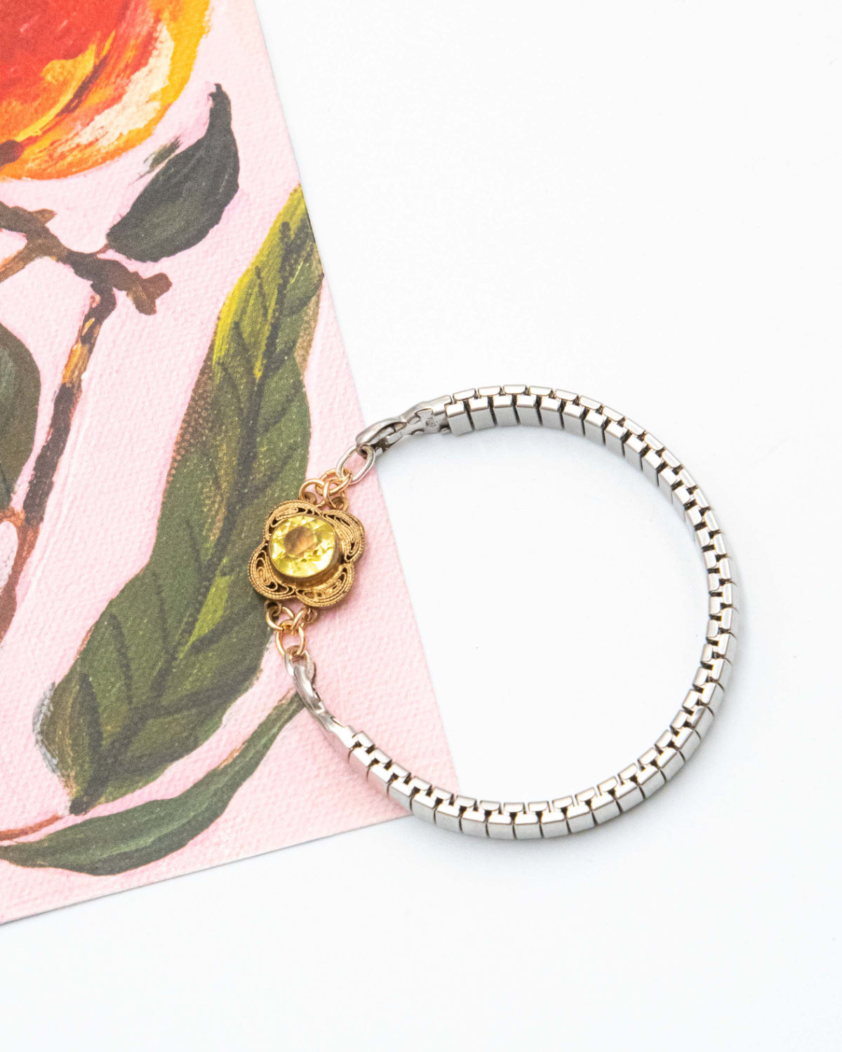 Silver expansion bracelet with a lemon quartz stone charm on a floral background