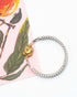 Silver expansion bracelet with a lemon quartz stone charm on a floral background