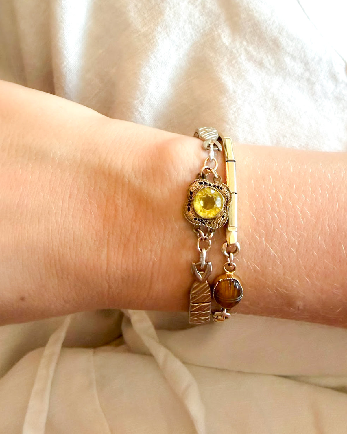 Close-up of a wrist wearing a vintage bracelet with a lemon quartz stone against a neutral background