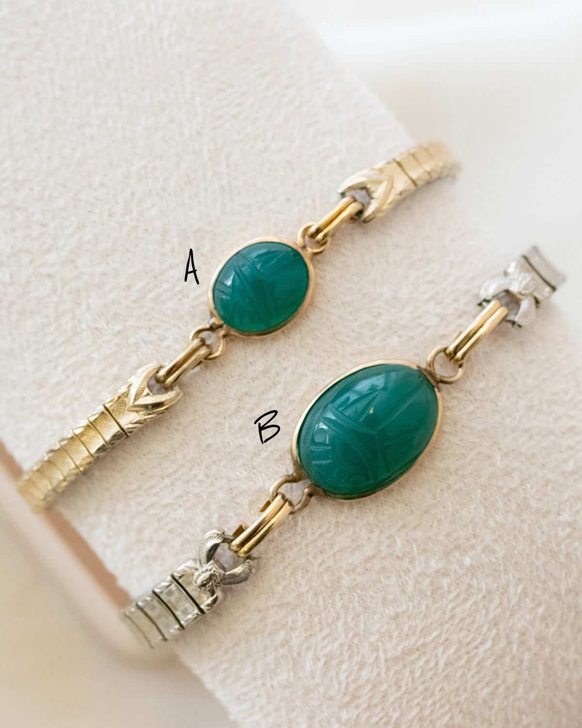Gold and silver bracelet with green scarab gemstones on a light background
