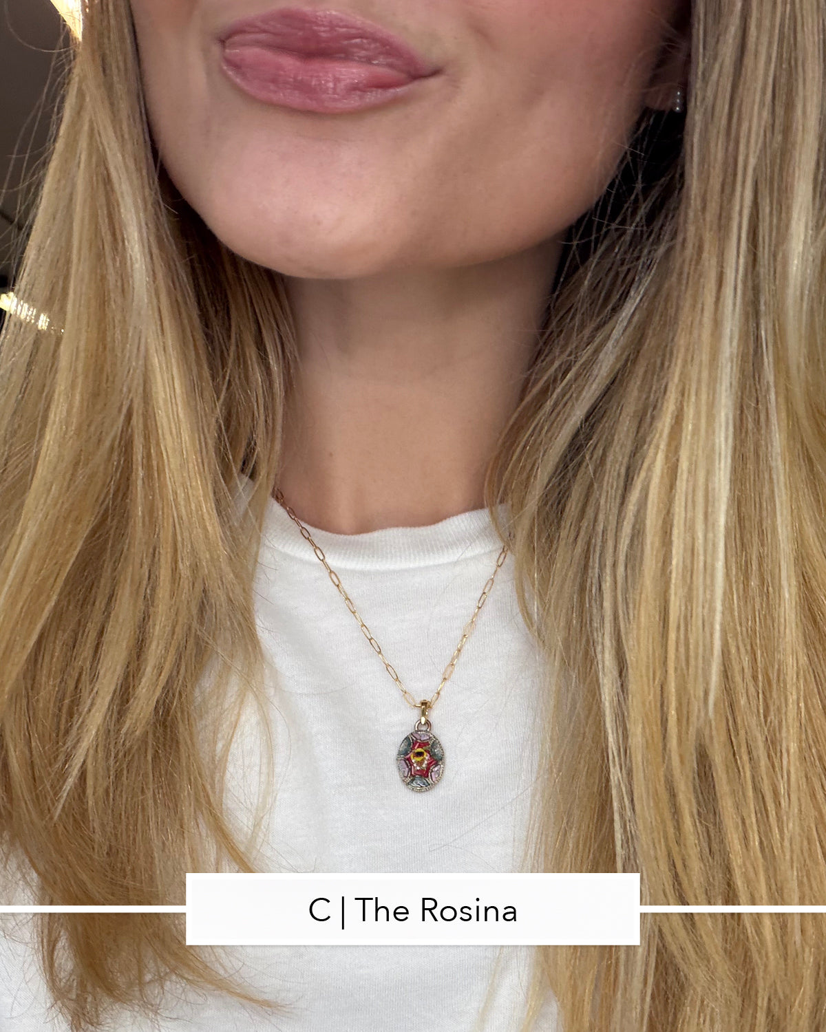 A close-up of a woman wearing a delicate gold chain necklace with a teardrop-shaped micro mosaic pendant featuring a colorful floral design, paired with a white crewneck t-shirt.