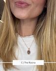 A close-up of a woman wearing a delicate gold chain necklace with a teardrop-shaped micro mosaic pendant featuring a colorful floral design, paired with a white crewneck t-shirt.