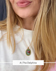 A close-up lifestyle shot of a woman wearing a gold chain necklace with an oval micro mosaic pendant featuring a colorful floral design.