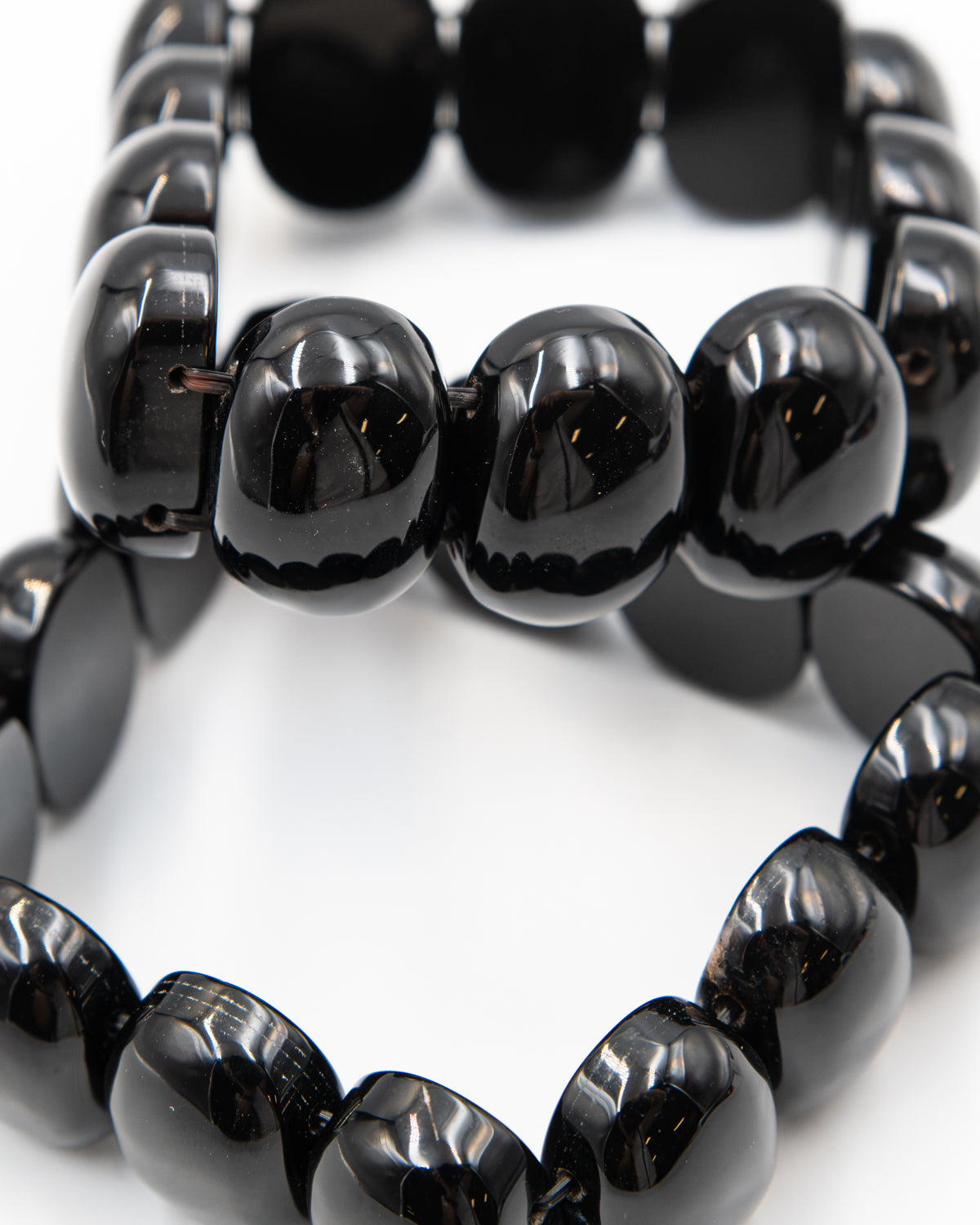 Close-up of two black onyx beaded bracelets stacked together, highlighting the glossy polished surface of the chunky stone beads.
