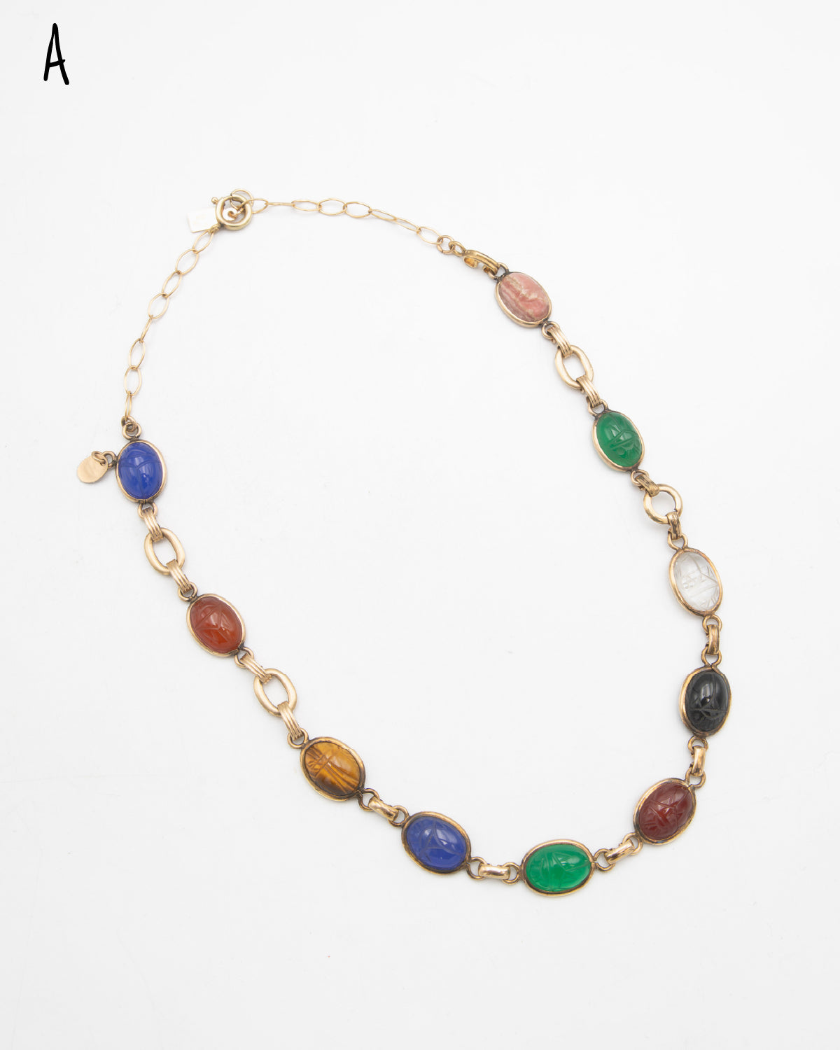 Vintage gold-filled necklace featuring multiple oval cabochon scarab gemstones carved with scarab beetle motifs in various colors including green, blue, brown, black, and red, set in gold links on a white background.