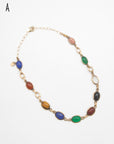Vintage gold-filled necklace featuring multiple oval cabochon scarab gemstones carved with scarab beetle motifs in various colors including green, blue, brown, black, and red, set in gold links on a white background.