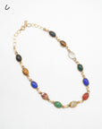 A vintage gold-filled chain necklace featuring a series of oval, multi-colored scarab stone beads in various patterns and hues, displayed on a clean white background.