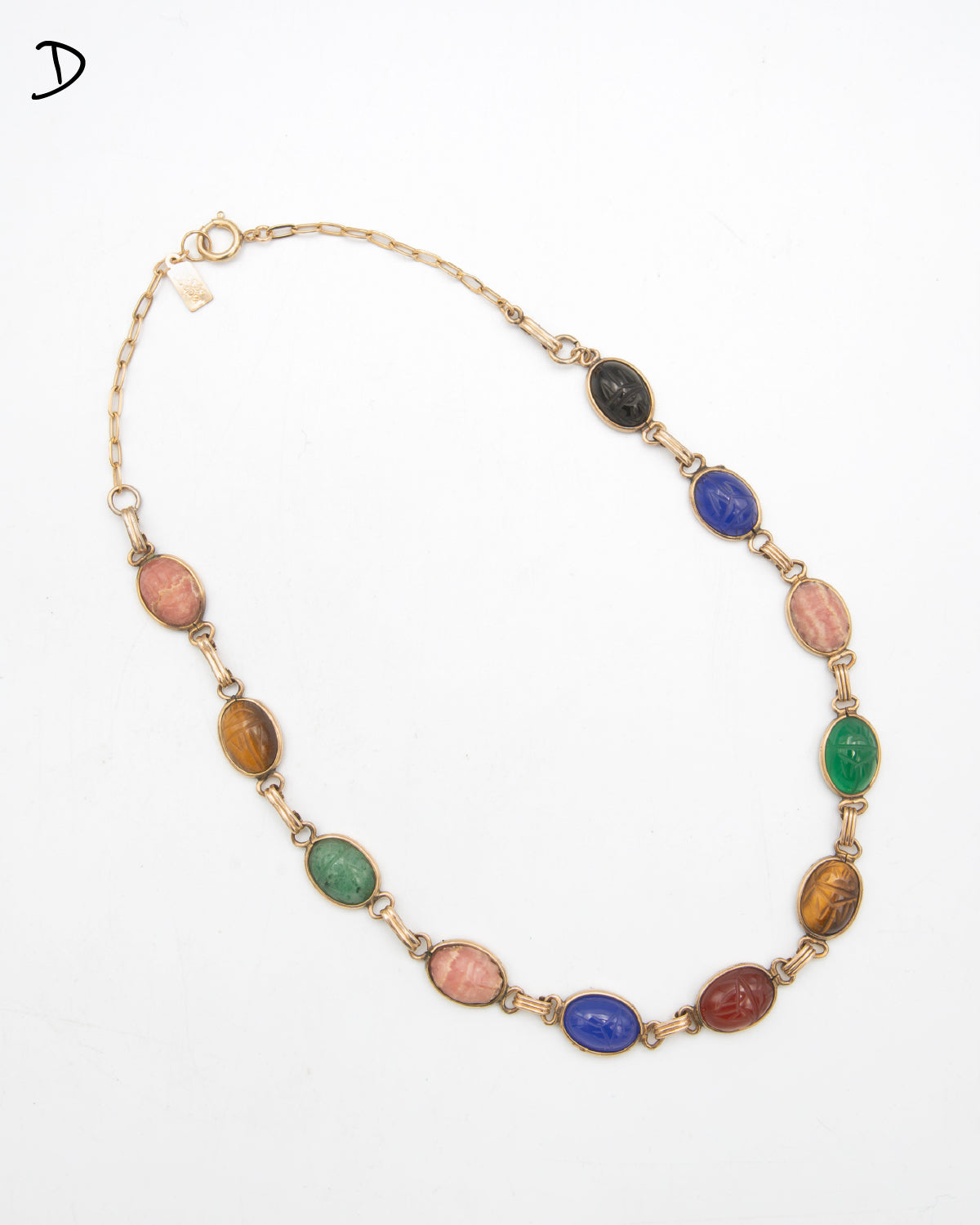 A gold-tone chain necklace featuring multiple oval cabochon gemstone beads in various colors including pink, green, blue, brown, and red, arranged in a circular layout on a white background.