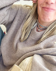 Woman in a lavender sweater wearing the silver locket on gray silk wrapped as a choker