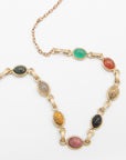 Close-up of two scarab gemstone necklaces overlapping, showcasing the carved beetle details in green, red, black, and pink stones.