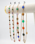 Four scarab beetle gemstone necklaces labeled A through D displayed side by side on a white jewelry stand.