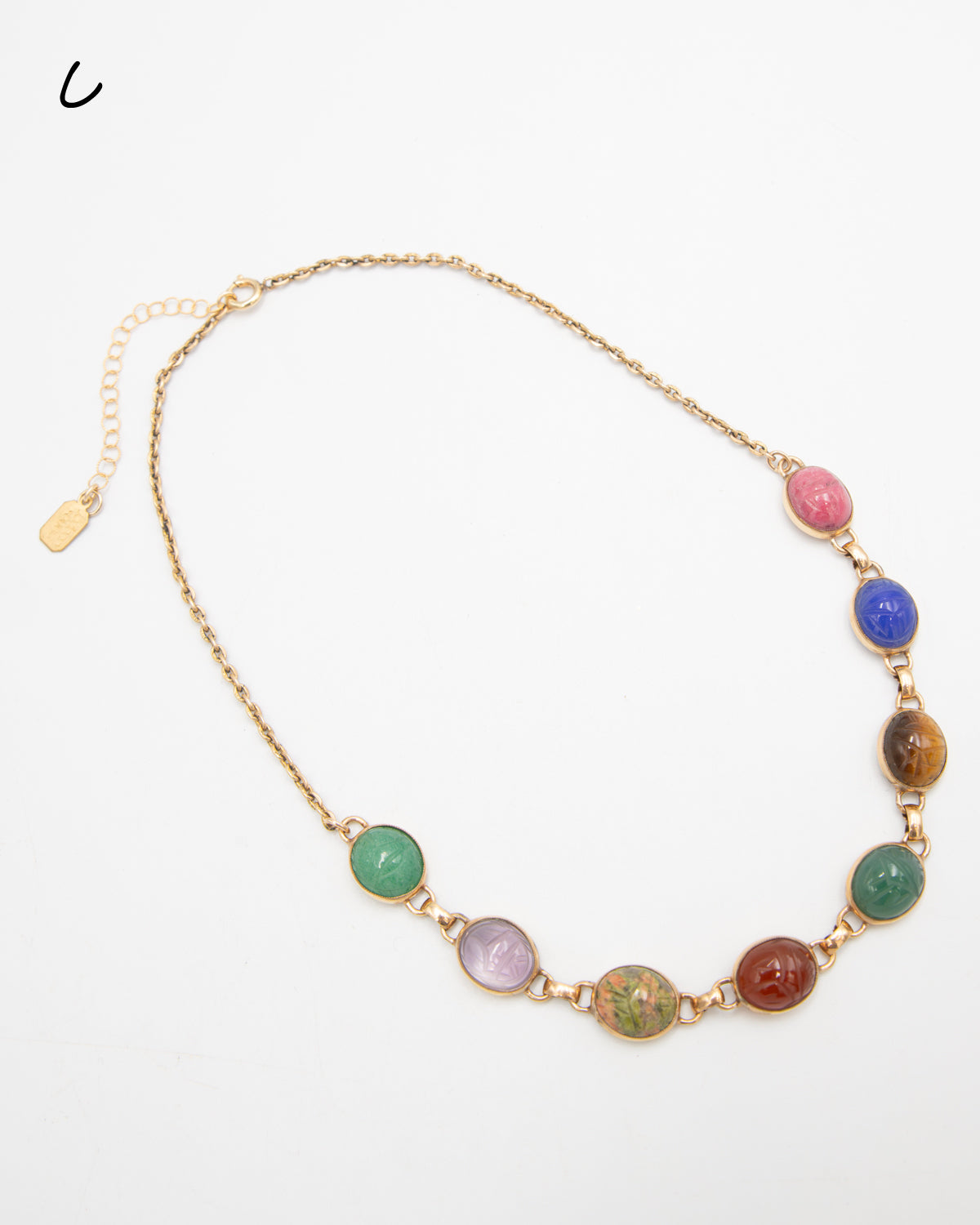 Scarab gemstone necklace with eight carved stone beetles in varied colors, including pink, blue, and green, photographed flat against a white background.